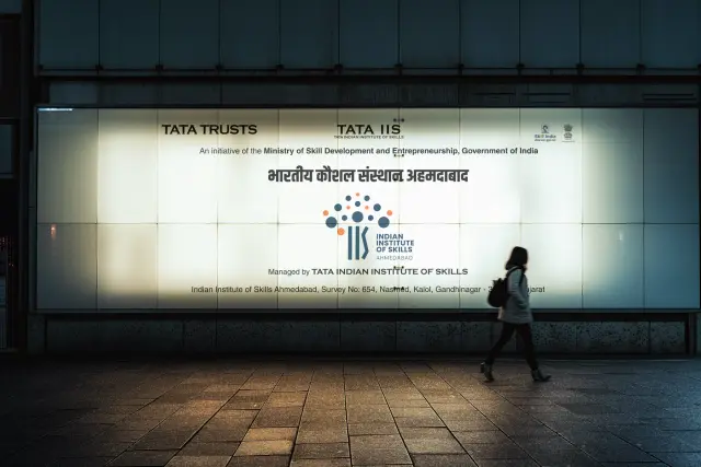 IIS Ahmedabad: Backlit city-light box, the mark read at night.